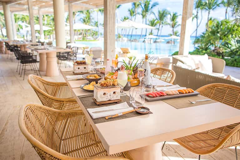 Elegant beachfront dining setup with rattan chairs and ocean views
