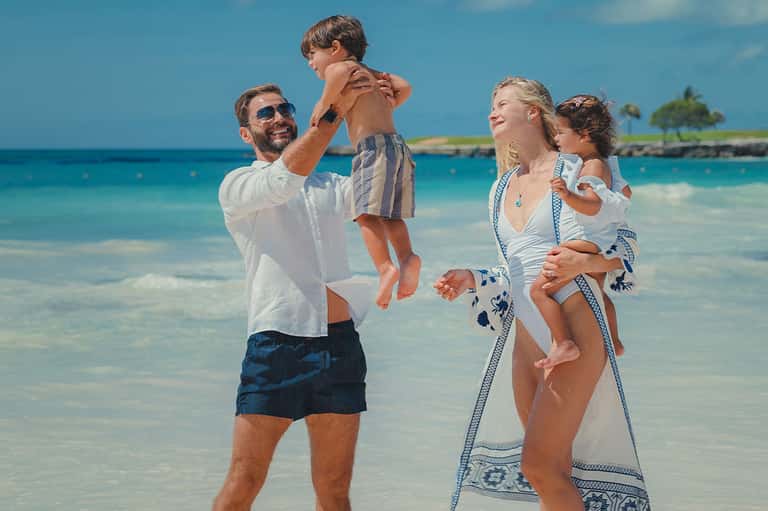 Family playing in shallow turquoise ocean water at tropical beach