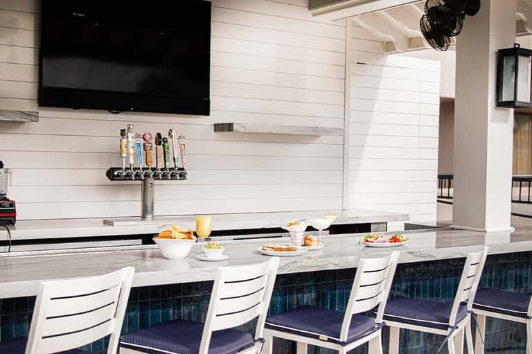 Modern lounge bar with white and navy seating, marble countertop, and craft beer tap system
