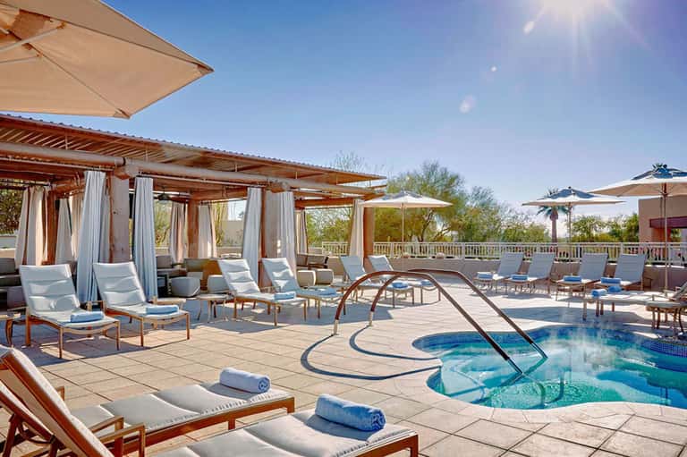 Luxury resort pool deck with cabanas, umbrellas, lounge chairs, and spa features