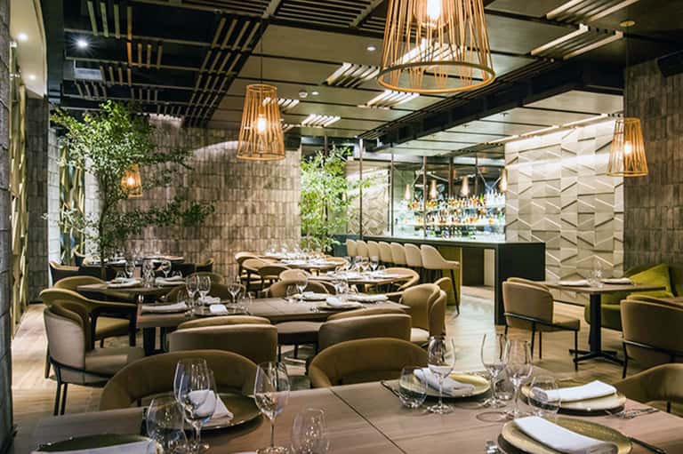 Upscale restaurant interior with elegant seating, pendant lighting, and green plants