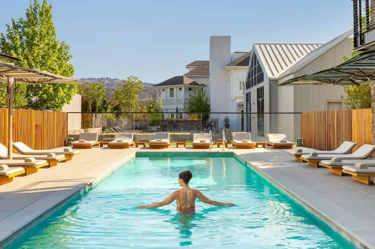 Resort swimming pool with lounge chairs and modern architectural building.