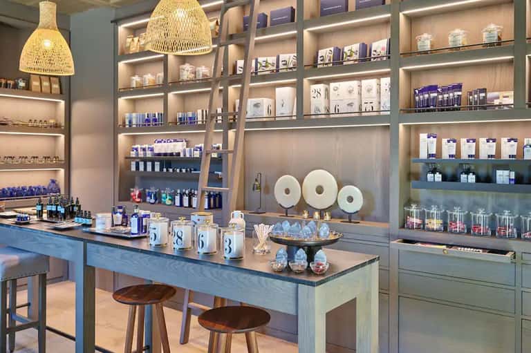 Spa retail shop with woven pendant lamp, shelving displays of products, and treatment counter