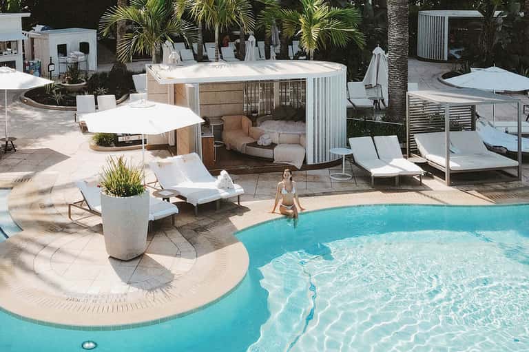Resort pool area with cabanas, loungers, umbrellas, and tropical landscaping