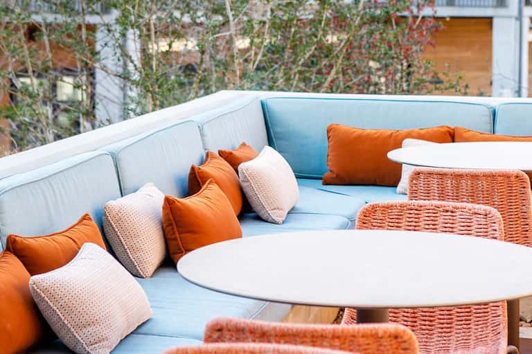 Outdoor lounge seating with light blue cushioned furniture and orange accent pillows