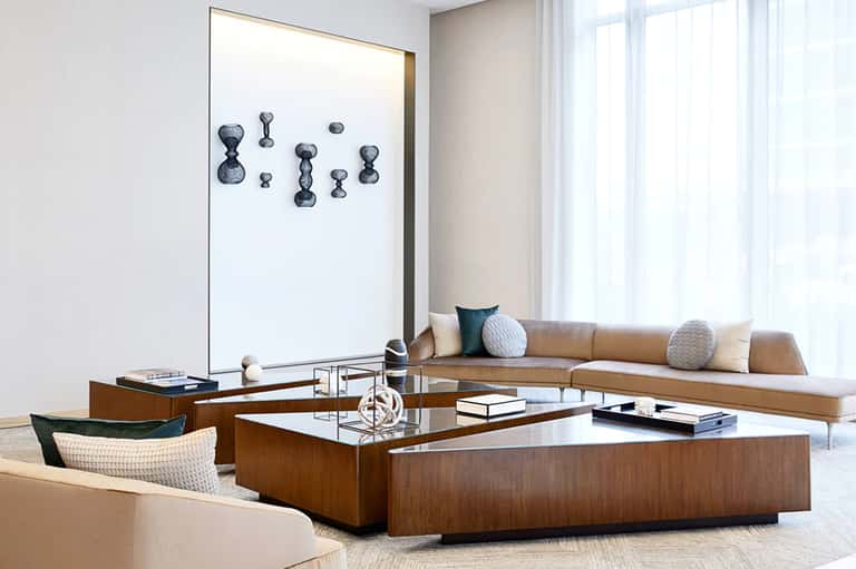 Modern hotel suite living area with tan sofa, wooden coffee table, and large abstract wall art
