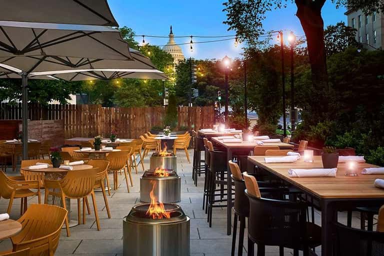 Rooftop dining area with fire pits and Capitol building view at twilight