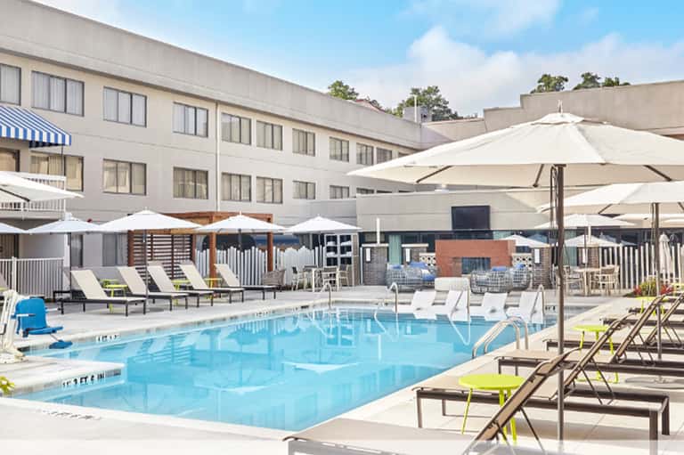 Resort pool with loungers, umbrellas and hotel building backdrop
