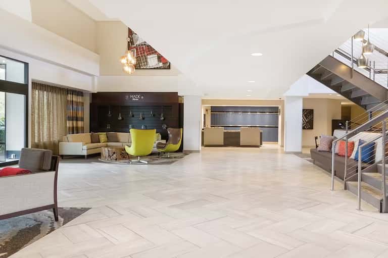 Modern hotel lobby with high ceilings, contemporary furniture, and staircase