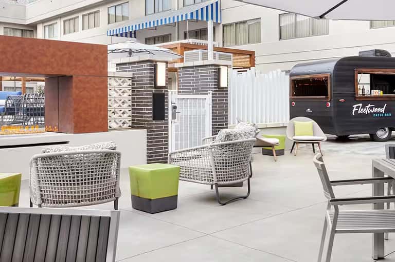 Modern resort courtyard with white wicker chairs, food truck, and contemporary architecture