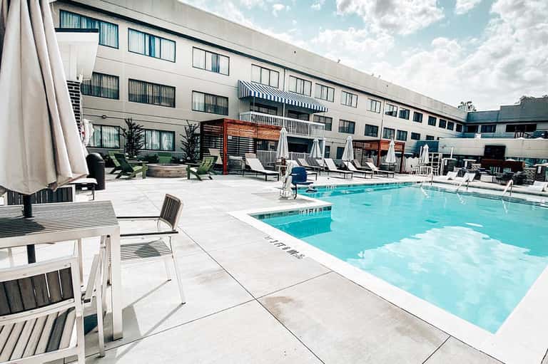 Hotel pool deck with lounge chairs, umbrellas, and modern building facade