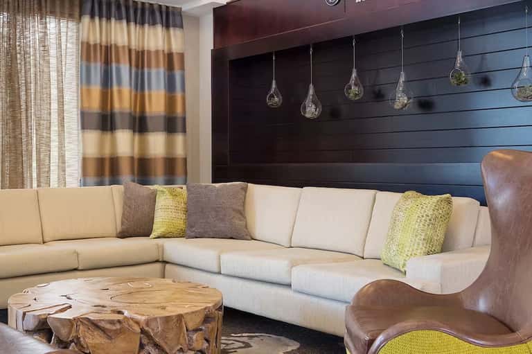 Modern lounge with cream sectional, striped curtains, and geometric wood table