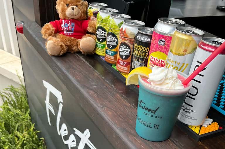 Poolside bar display with craft beers, cocktail drinks, and teddy bear decoration