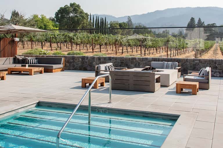 Resort pool overlooking vineyard landscape with lounge seating and fire pit