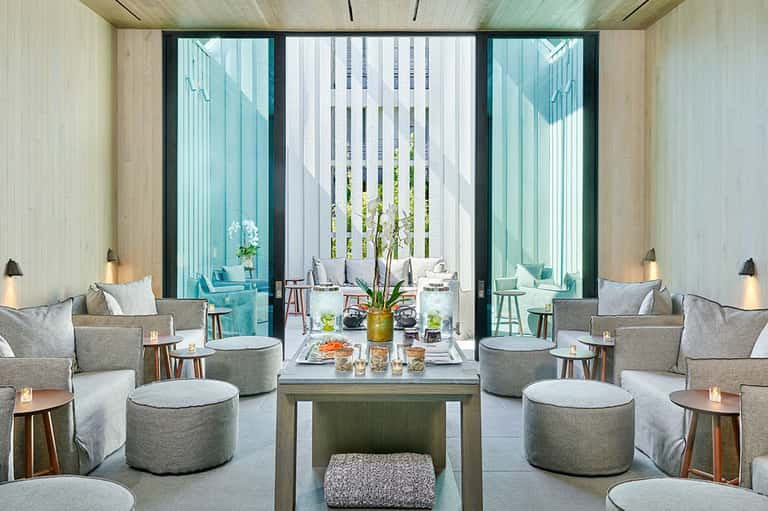 Modern lounge with gray seating, turquoise glass doors, and minimalist decor