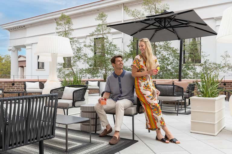 Rooftop terrace with modern outdoor furniture, black umbrella, and neoclassical building backdrop