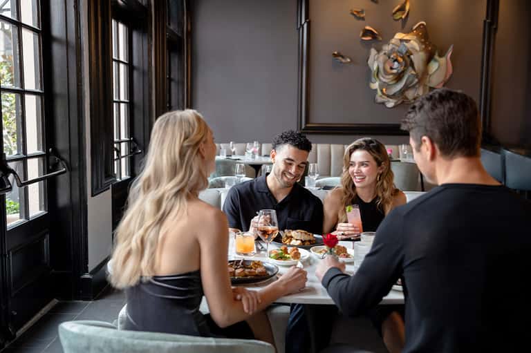 Four guests dining together at elegant restaurant with dark walls and artwork