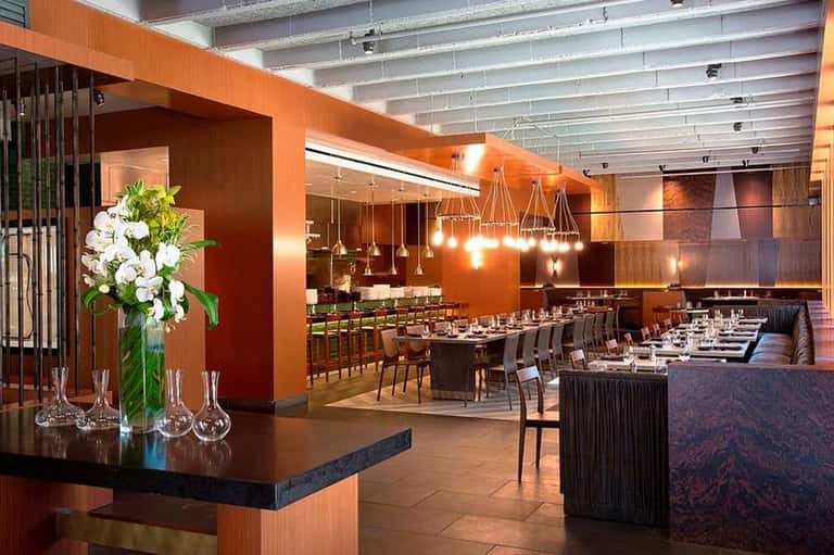 Upscale restaurant interior with orange walls, pendant lighting, and modern furnishings