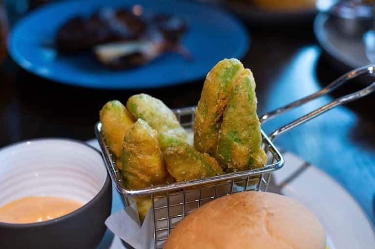 Gourmet appetizer plate with fried pastries, dipping sauce, and blue dinnerware at upscale restaurant