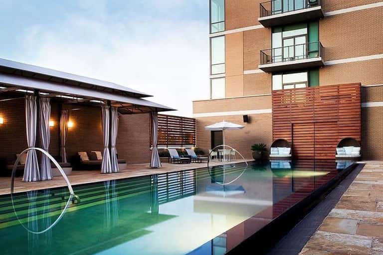 Rooftop pool deck with modern pergolas, lounge chairs, and apartment building backdrop