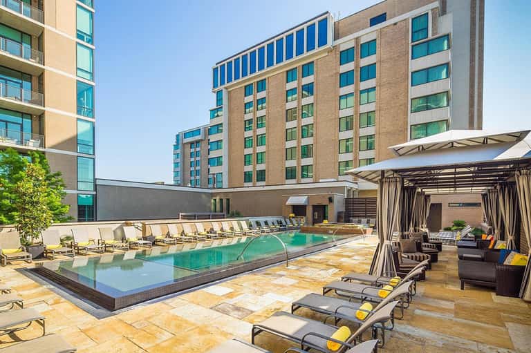 Rooftop hotel pool with loungers, pergolas, and apartment buildings surrounding