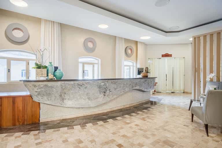 Elegant hotel lobby with curved marble reception desk, arched doorways, and sophisticated décor