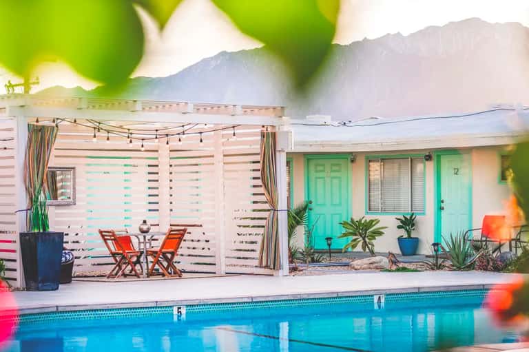 Mid-century modern poolside cabana with turquoise doors and mountain backdrop