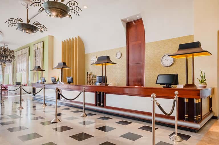 Elegant hotel lobby with long wooden check-in desk, art deco lighting, and polished floor