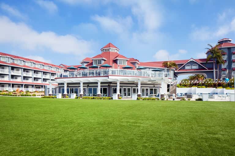 Grand beachfront resort with red roof and manicured lawn overlooking ocean