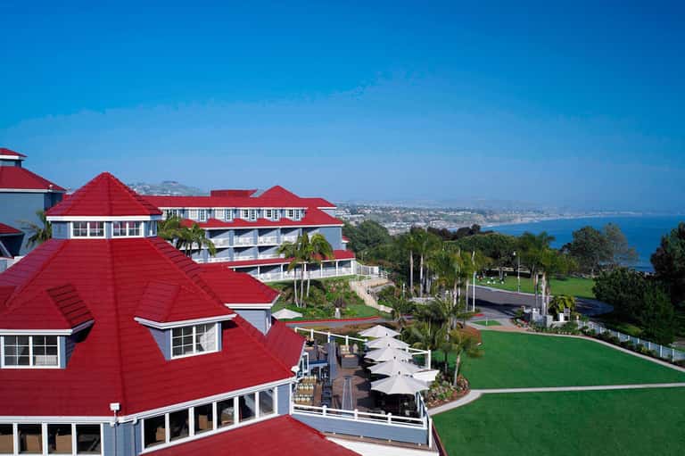 Hilltop resort building with distinctive red roofing overlooking coastal landscape and ocean