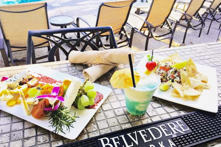 Poolside dining with colorful appetizers and cocktails on white plates at a resort restaurant