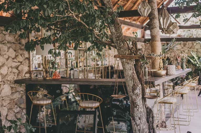 Rustic courtyard bar with stone walls, wooden chairs, and vintage decorative elements