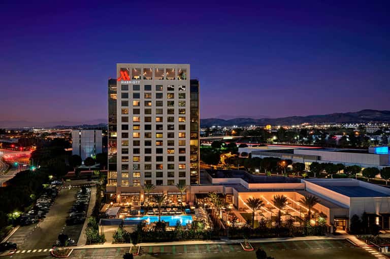 Marriott hotel exterior at dusk illuminated against purple sky with pool and landscaping