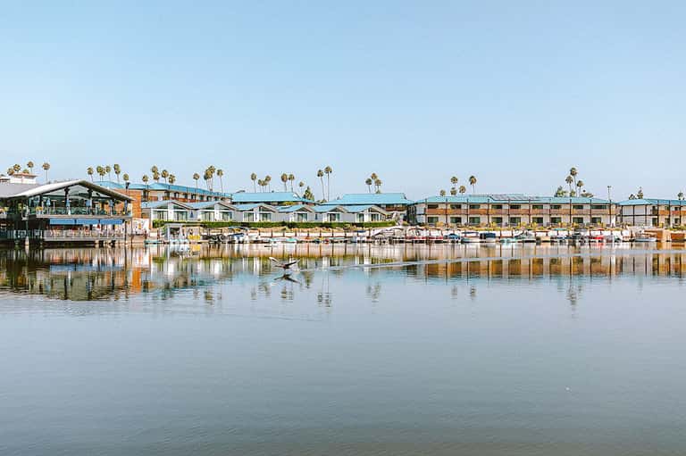 Waterfront resort with turquoise roofs and palm trees reflected in calm bay water