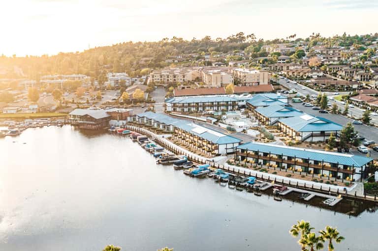 Waterfront resort with blue metal-roofed buildings along calm river at golden hour