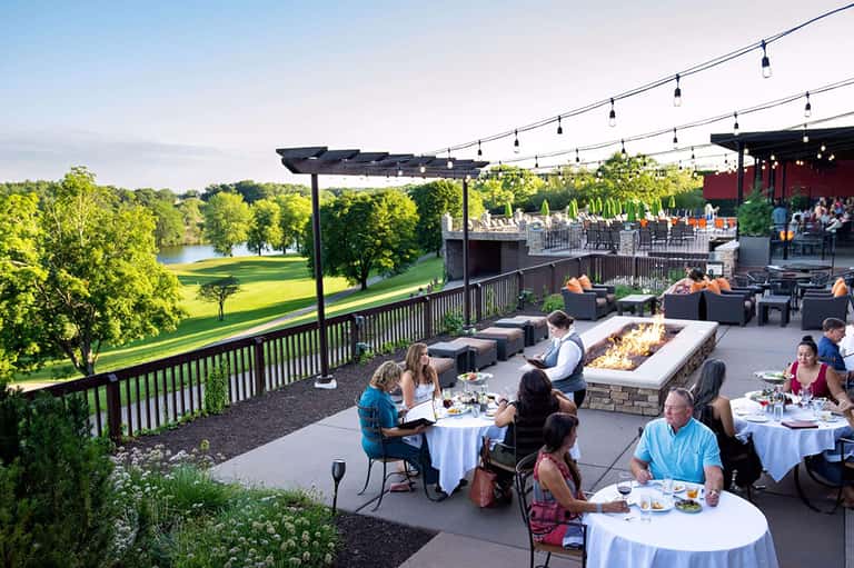 Outdoor event venue with fire pit, tables, and views of golf course and river landscape