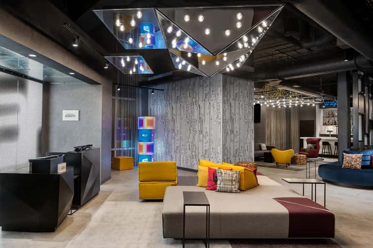 Modern hotel lobby with colorful seating, geometric ceiling lights, and contemporary design
