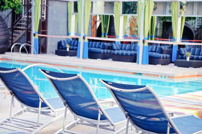 Resort pool with blue lounge chairs and striped cushioned seating on the deck
