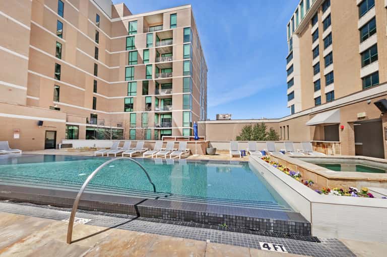 Urban apartment complex with outdoor pool, lounge chairs, and surrounding brick buildings