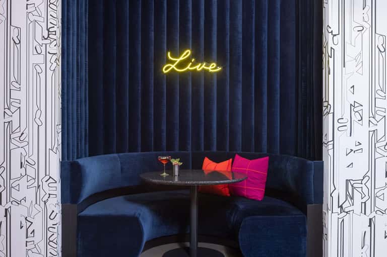 Upscale lounge booth with blue seating and neon 'Live' sign