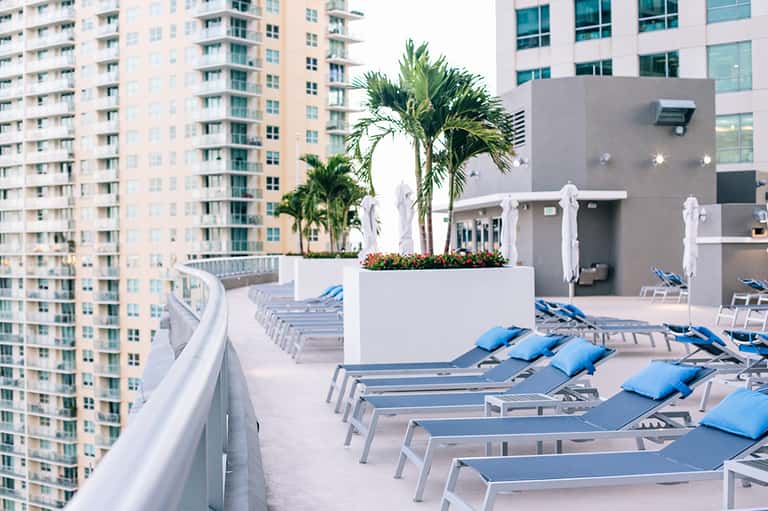 High-rise rooftop pool deck with lounge chairs and city skyline backdrop