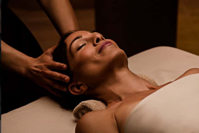 Woman receiving professional head and neck massage in spa treatment room