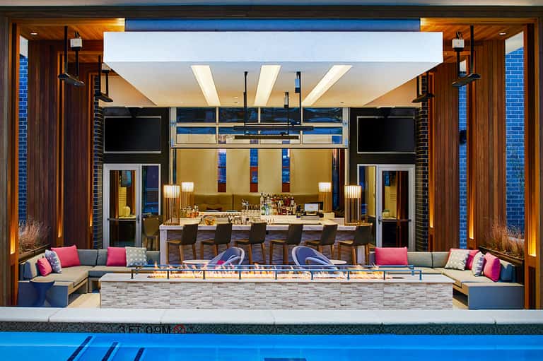 Modern resort courtyard with lounge seating, bar area, fire pit and pool access