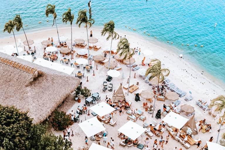 Aerial view of busy beach resort with umbrellas, loungers, and turquoise ocean