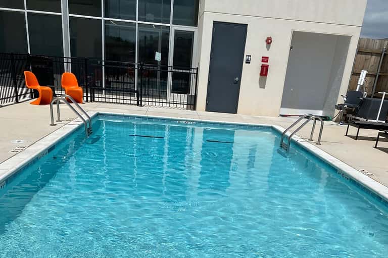 Rectangular hotel pool with turquoise water and orange chairs on outdoor patio