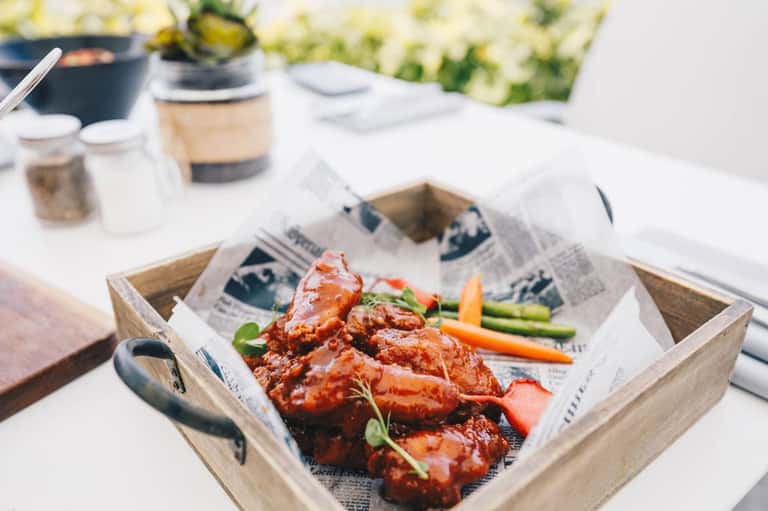 Grilled meat appetizers served in wooden tray at outdoor resort dining table