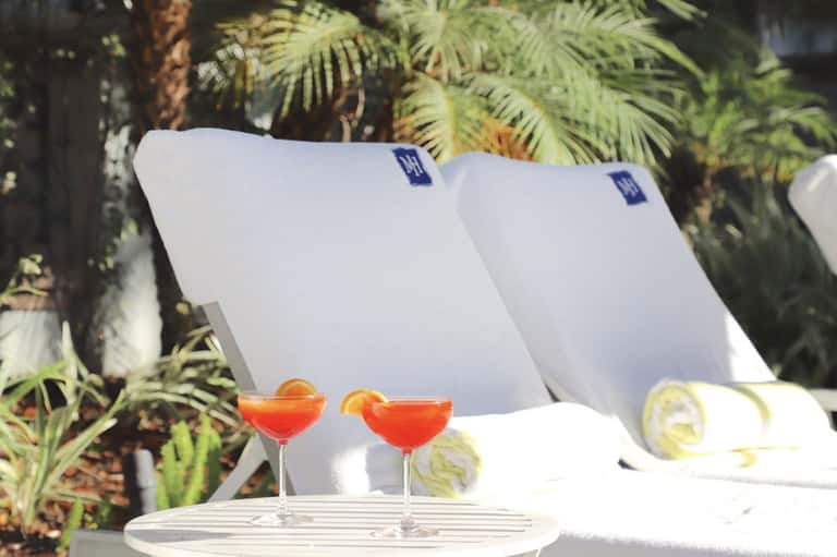 Poolside cocktails with citrus garnish and white lounge chairs in tropical setting
