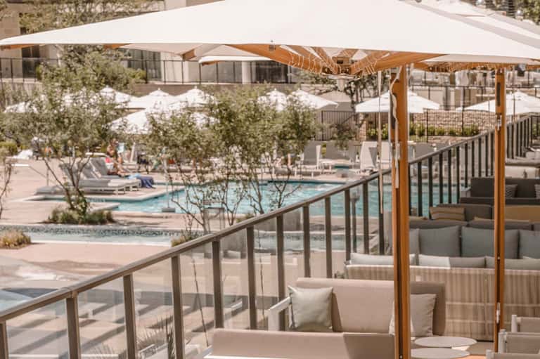 Outdoor terrace with shaded seating overlooking resort pool and grounds with umbrellas
