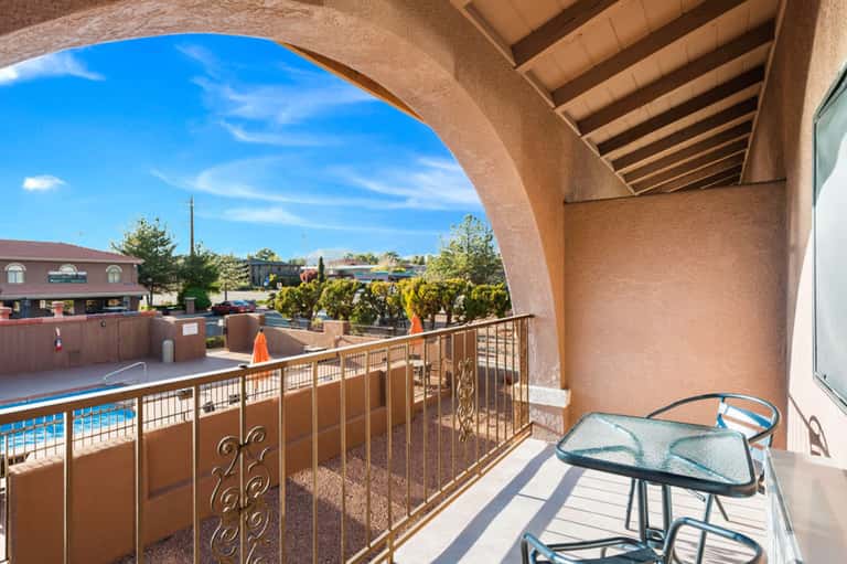 Balcony overlooking resort pool and grounds with railing and patio furniture