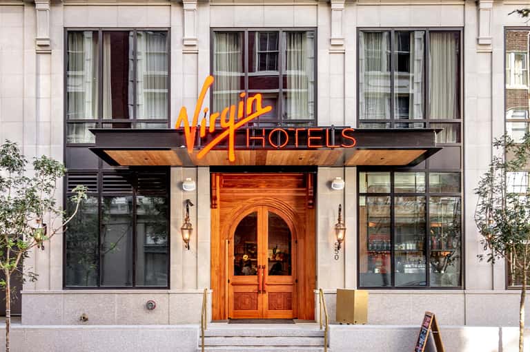 Virgin Hotels entrance with iconic red and yellow signage, wooden doors, and modern storefront